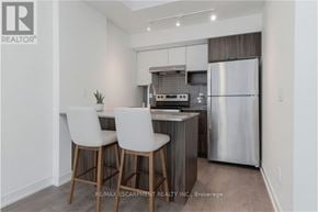 Burlington (Lasalle) townhouse for rent - A modern kitchen with white chairs and a stainless steel refrigerator.