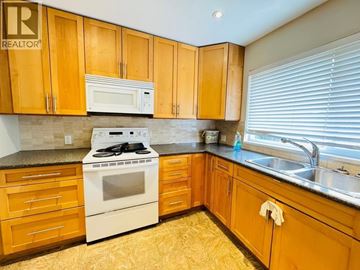 Richmond apartment for rent - A kitchen with wooden cabinets and a white stove top oven.