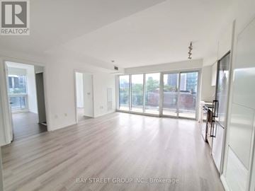 Toronto (Moss Park) condo for rent - A spacious room with wooden flooring and large windows.