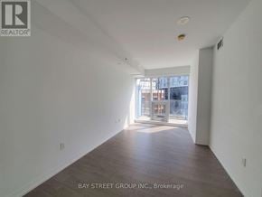 Toronto (Moss Park) condo for rent - A spacious room with wooden floors and a large window.