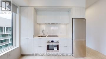 Toronto (Regent Park) condo for rent - A kitchen with white cabinets and a refrigerator.