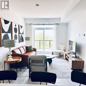 Collingwood condo for rent - A living room with a brown leather couch, a grey armchair, a wooden side table, and a television.