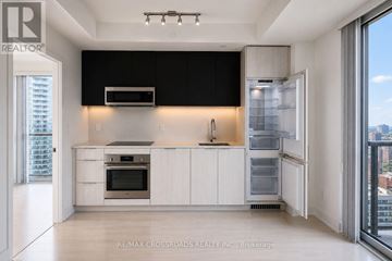 Toronto (Church-Yonge Corridor) condo for rent - A modern kitchen with white cabinets and a black backsplash.