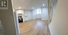 Toronto (University) apartment for rent - A spacious room with wooden flooring and white walls, furnished with a dining table and chairs.