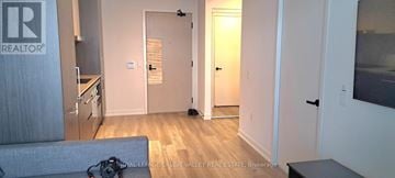 Vaughan (Vaughan Corporate Centre) condo for rent - A living room with a grey couch and a wooden floor.