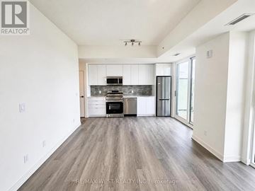 Brantford condo for rent - A spacious kitchen with white cabinets and a wooden floor.