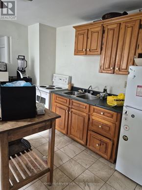 Toronto (Greenwood-Coxwell) apartment for rent - A kitchen with wooden cabinets and a white fridge.