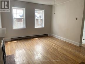 Stratford multi-family for rent - A room with wooden flooring and two windows.