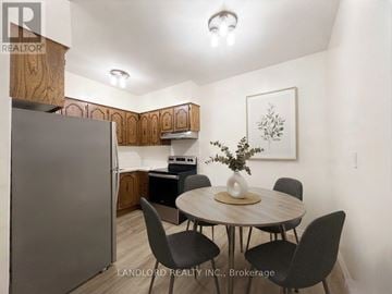 Toronto (Roncesvalles) multi-family for rent - A kitchen with a table and chairs in the foreground and a refrigerator in the background.