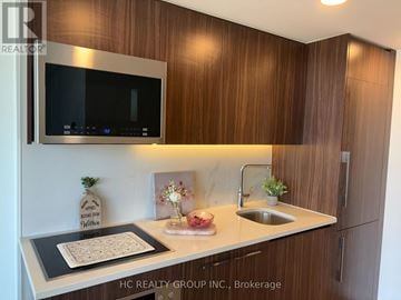 Toronto (Waterfront Communities) condo for rent - A kitchen with wooden cabinets and a microwave above the counter.