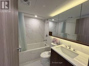 Toronto (Waterfront Communities) condo for rent - A bathroom with a marble wall and a wooden door.