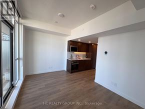 Toronto (Waterfront Communities) condo for rent - A spacious room with wooden flooring and a kitchenette in the corner.