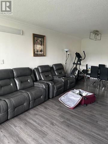 Toronto (L'amoreaux) condo for rent - A living room with a grey leather couch and a red suitcase on the floor.