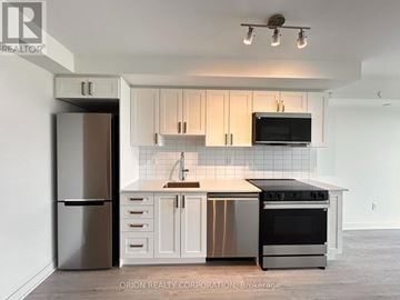 Pickering (Bay Ridges) condo for rent - A kitchen with white cabinets and a black fridge.