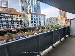 Waterloo condo for rent - A balcony with a railing overlooks a cityscape with buildings and cars.