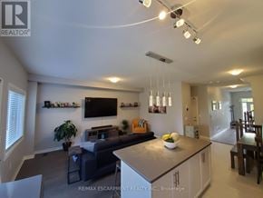 Lincoln (Beamsville) townhouse for rent - A modern living room with a grey couch and a flat screen TV mounted on the wall.