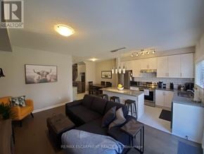 Lincoln (Beamsville) townhouse for rent - A living room with a couch and a kitchen in the background.