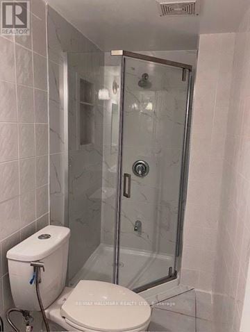 Toronto (Hillcrest Village) apartment for rent - A white toilet with a towel rack and a glass shower stall with a door.