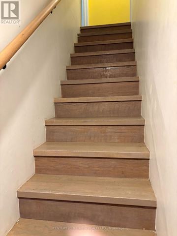 Orillia fourplex for rent - A set of wooden stairs with a handrail on the left side.