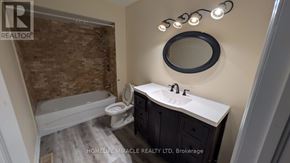 Brampton (Madoc) apartment for rent - A bathroom with a toilet, sink, and a round mirror.