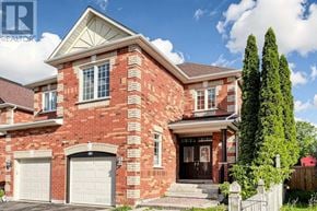 Richmond Hill (Rouge Woods) townhouse for rent - A red brick house with a white garage door and a black gate.
