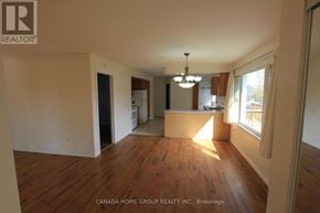 Innisfil apartment for rent - A large empty room with wood flooring and a chandelier.