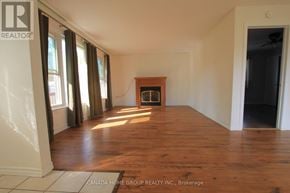 Innisfil apartment for rent - A room with wooden floors and a fireplace in the middle.