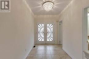 Brampton (Vales Of Castlemore) apartment for rent - A hallway with a chandelier and a glass door with a clock on it.