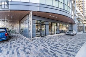 Kitchener condo for rent - A modern building with a glass entrance and a blue car parked in front.