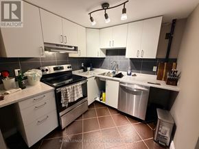 Wasaga Beach apartment for rent - A kitchen with white cabinets and a black stove top oven.