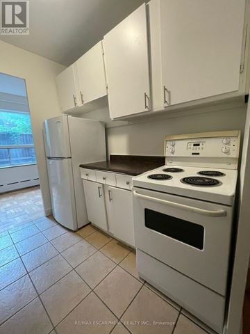 Hamilton (Durand) multi-family for rent - A white kitchen with a stove and cabinets.