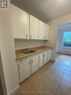 Hamilton (Durand) multi-family for rent - A kitchen with white cabinets and a tiled floor.