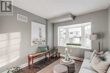Oakville (Cp College Park) apartment for rent - A living room with a grey couch, a wooden bench, and a painting of a deer on the wall.
