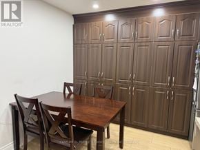 Mississauga (Meadowvale) apartment for rent - A brown wooden dining table with four chairs in front of a wall with a logo that says REALTOR.
