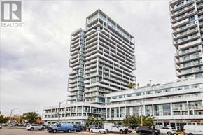 Oakville (Co Central) condo for rent - A tall building with a glass facade stands in front of a smaller building with a parking lot in the foreground.