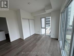 Newmarket (Huron Heights-Leslie Valley) condo for rent - A room with wooden flooring and a large window overlooking a balcony.