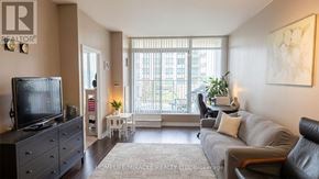 Burlington (Uptown) condo for rent - A living room with a couch, a television, and a plant.