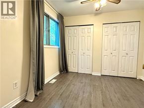 Kitchener apartment for rent - A room with a window, two doors, and a ceiling fan.