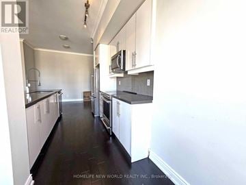 Mississauga (City Centre) condo for rent - A kitchen with white cabinets and black countertops.