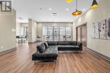 Mississauga (Hurontario) condo for rent - A spacious living room with a black couch and wooden floors.
