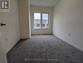 Oshawa (Samac) townhouse for rent - A room with a carpeted floor and a window showing a view of a building outside.