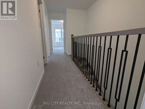 Oshawa (Samac) townhouse for rent - A hallway with a carpeted floor and a black railing on the right side.