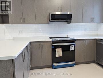 Oshawa (Samac) townhouse for rent - A kitchen with a white counter top and a microwave on a blue cart.