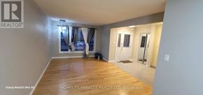 Mississauga (Clarkson) apartment for rent - A spacious room with wooden flooring and a large window with curtains.