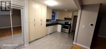 Mississauga (Clarkson) apartment for rent - A kitchen with white cabinets and a black countertop.