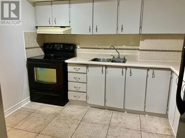 Ottawa condo for rent - A kitchen with white cabinets and a black stove top oven.