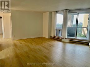 Ottawa condo for rent - A room with wooden flooring and a large window overlooking a balcony.