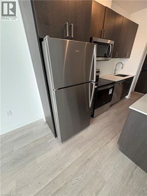 Hamilton condo for rent - A modern kitchen with a stainless steel refrigerator and wooden cabinets.
