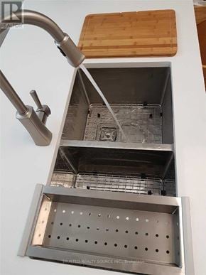 Toronto (Yonge-Eglinton) condo for rent - A kitchen sink with a faucet and a wooden cutting board above it.