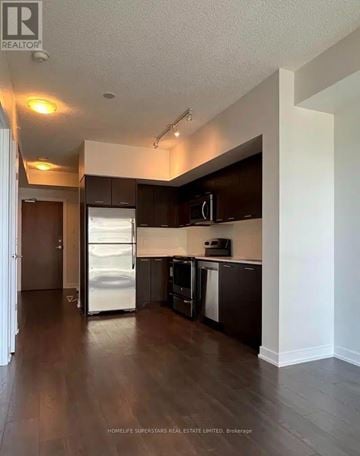 Toronto (Mimico) condo for rent - A kitchen with dark wood floors and white appliances.